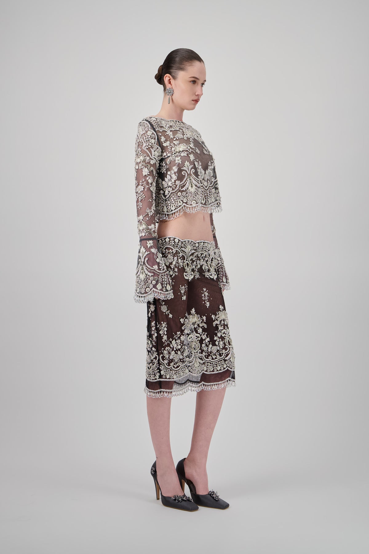 Volcanic Grey tulle midi skirt with intricate floral embroidery, ornate beadwork, sheer detailing and delicate beaded fringe.
Cropped tulle top with long sheer sleeves, intricate floral embroidery, ornate beadwork and delicate beaded fringe.
