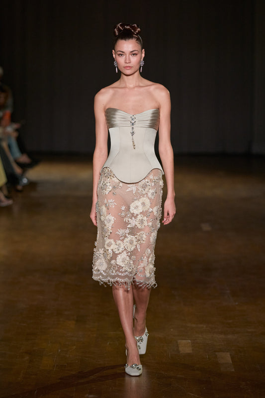 Strapless corset top with pleated satin bust and jeweled detail, paired with a sheer floral-embroidered midi skirt with beaded embellishments.