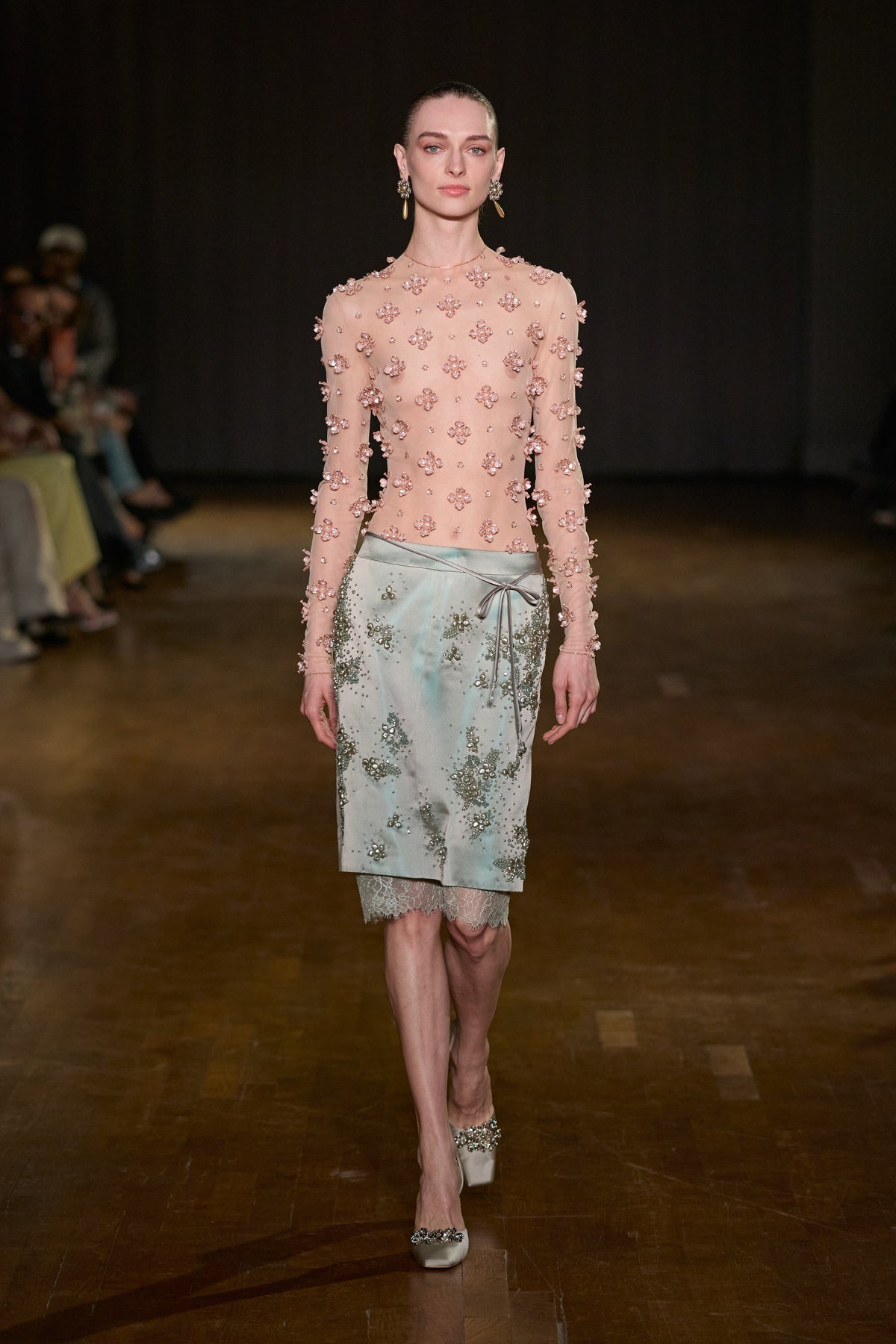 Sheer nude tulle top with pink floral embellishments, paired with a crystal-embellished satin midi skirt with lace trim.