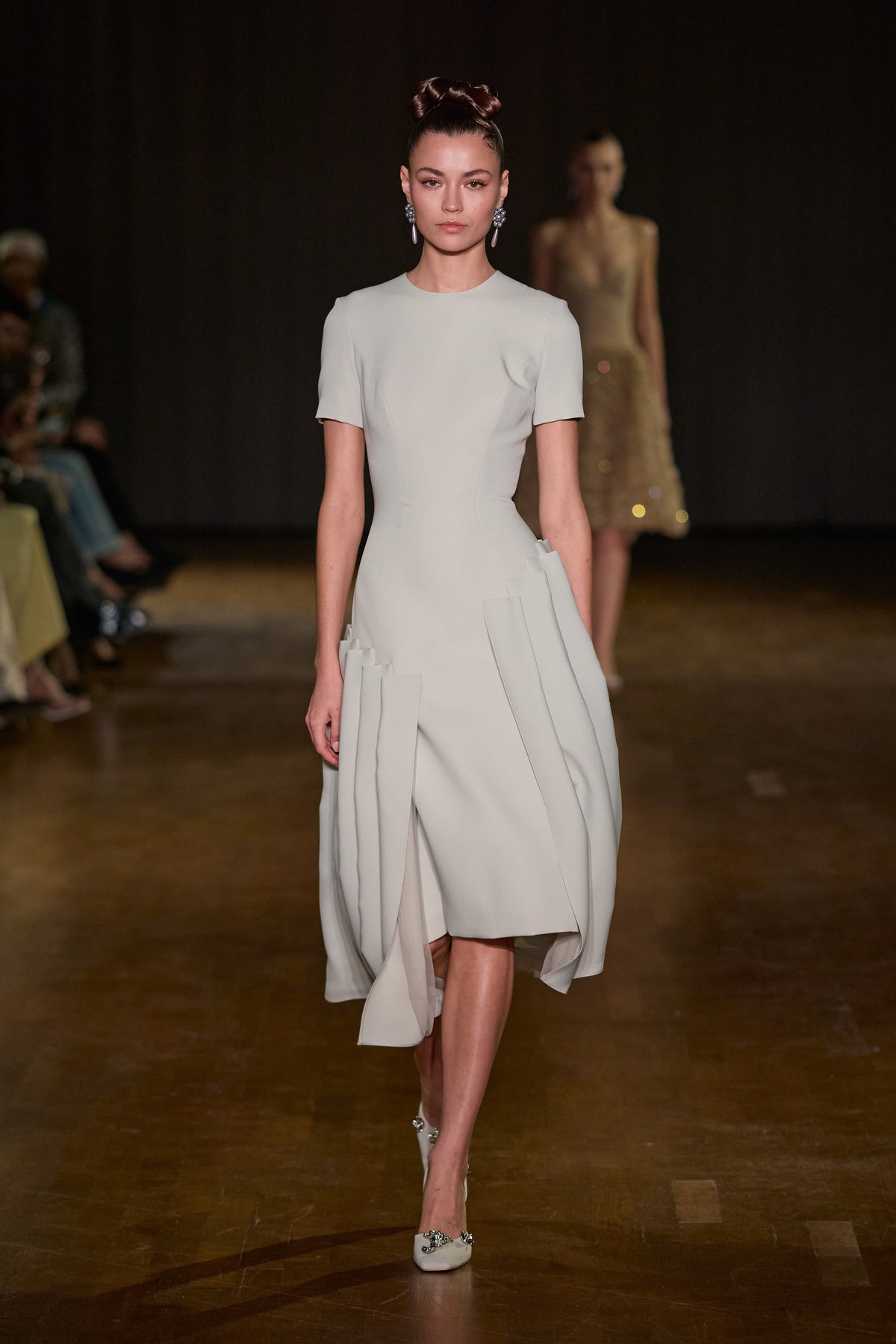 Ivory midi dress with short sleeves, a fitted waist and asymmetric sculptural pleated panels.