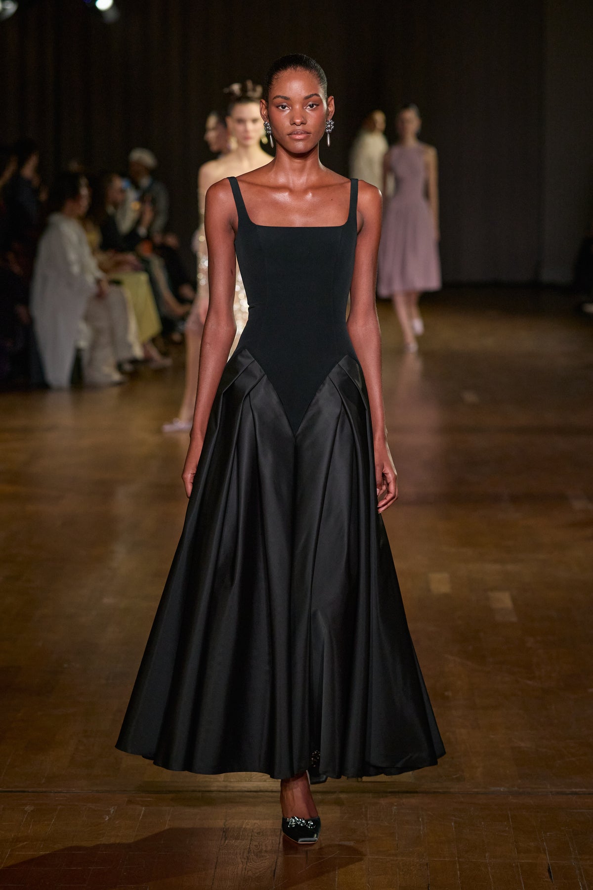 Black midi dress with a fitted square-neck bodice, sculpted hip detailing and a voluminous satin skirt.