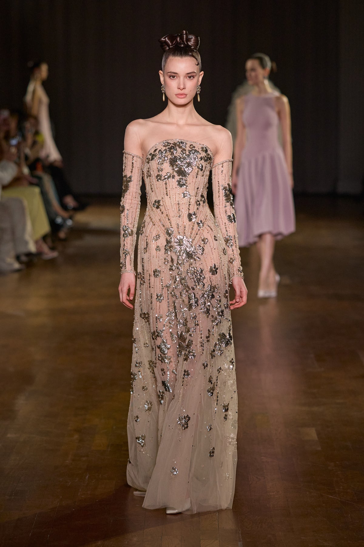 Nude off-shoulder maxi dress with sheer long sleeves and intricate metallic floral embellishments.