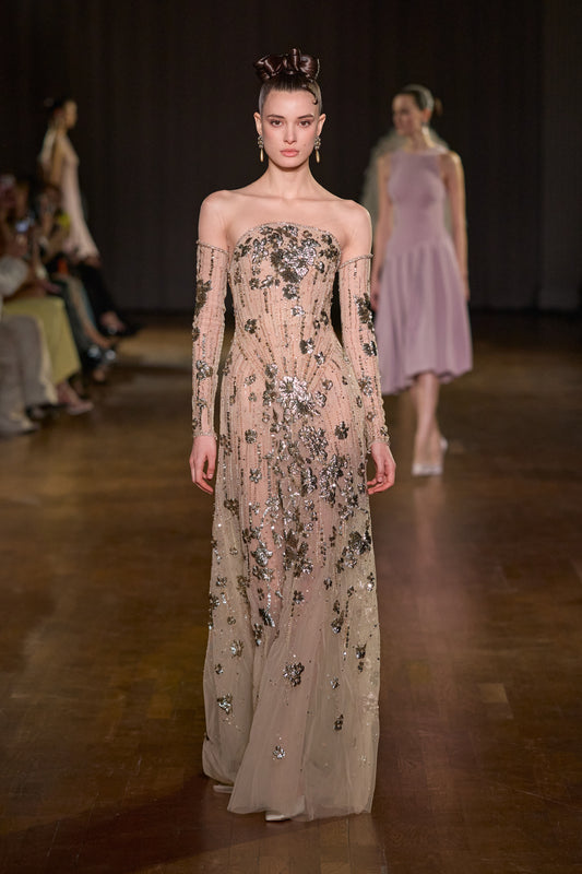 Nude off-shoulder maxi dress with sheer long sleeves and intricate metallic floral embellishments.