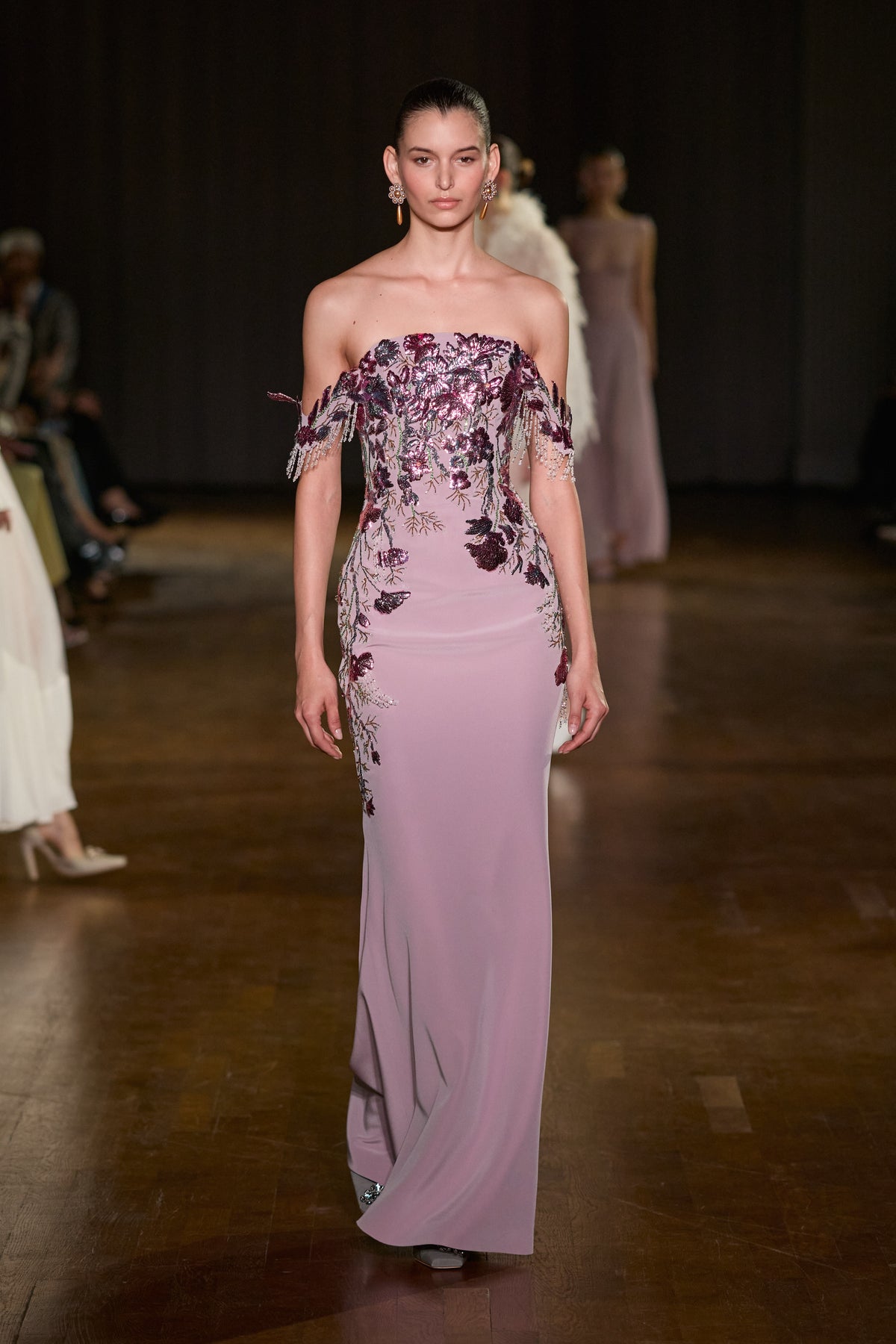 Pink off-shoulder maxi dress with floral embellishments and delicate beaded fringe detailing.