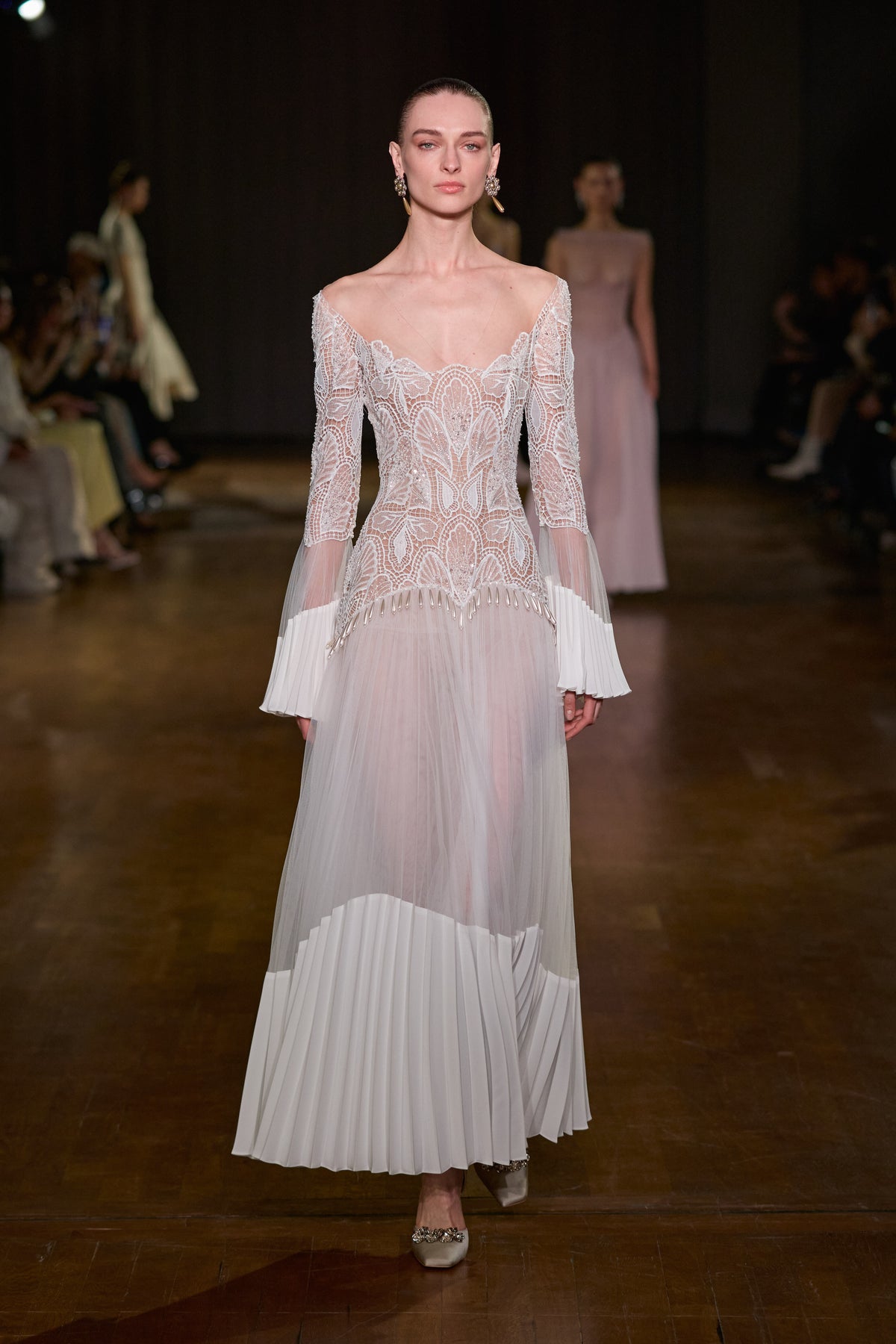 Ivory maxi dress with an intricate lace bodice, sheer long sleeves and pleated detailing at the cuffs and hem.