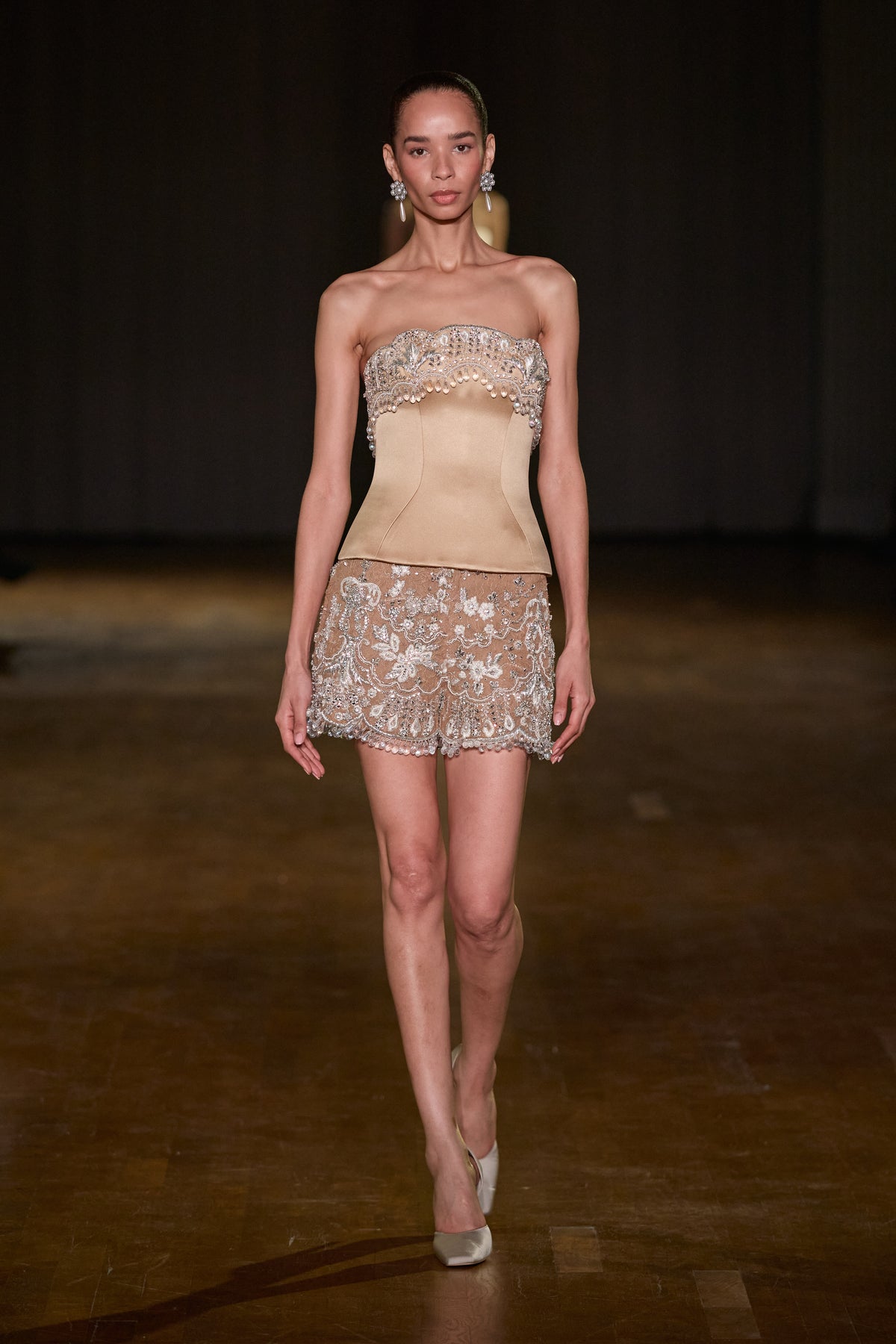 Beige satin corset with crystal and pearl embellishment paired with sheer embroidered mini shorts.