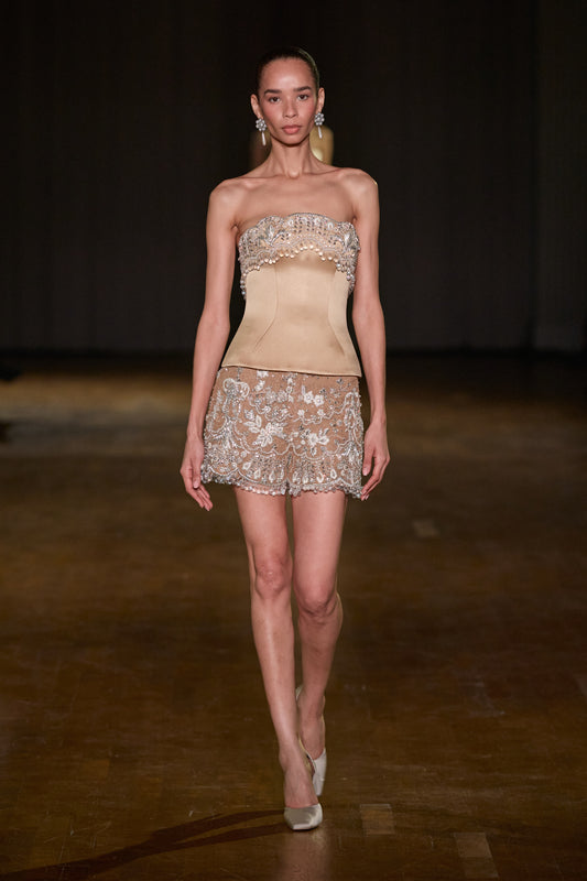 Beige satin corset with crystal and pearl embellishment paired with sheer embroidered mini shorts.
