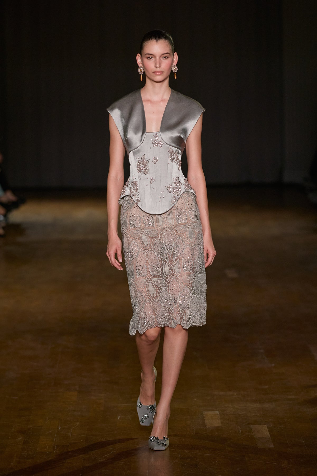 Embellished structured corset top with satin shoulder detailing, paired with an embroidered lace midi skirt with crystal accents.