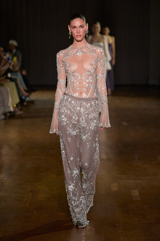 Sheer crystal-embellished bodysuit with flared sleeves, paired with embellished lace pants layered over wool.