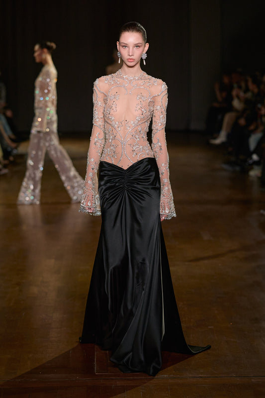 Sheer crystal-embroidered long-sleeve bodice with black satin floor-length skirt and gathered waist detail.