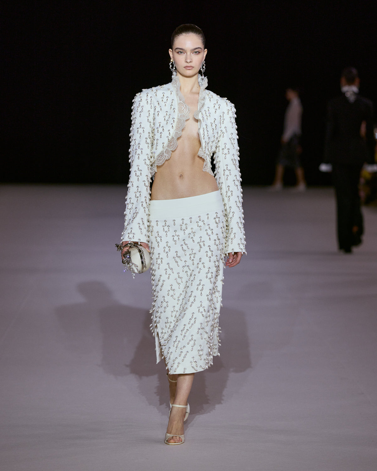 White cropped jacket with crystal embellishments and scalloped lace trim, paired with a matching embellished midi skirt.