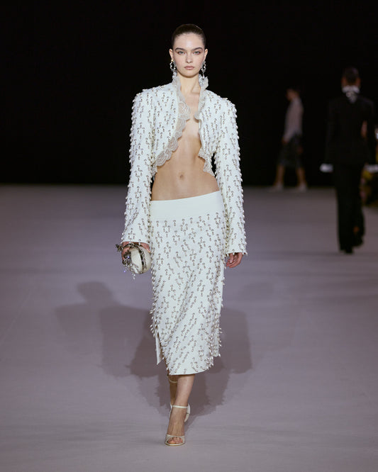 White cropped jacket with crystal embellishments and scalloped lace trim, paired with a matching embellished midi skirt.